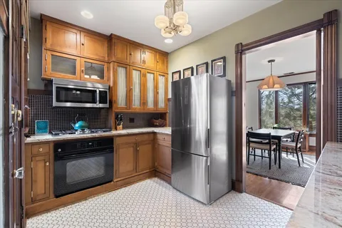 a kitchen with stainless steel appliances granite countertop a refrigerator a stove a sink a dining table and chairs with wooden floor