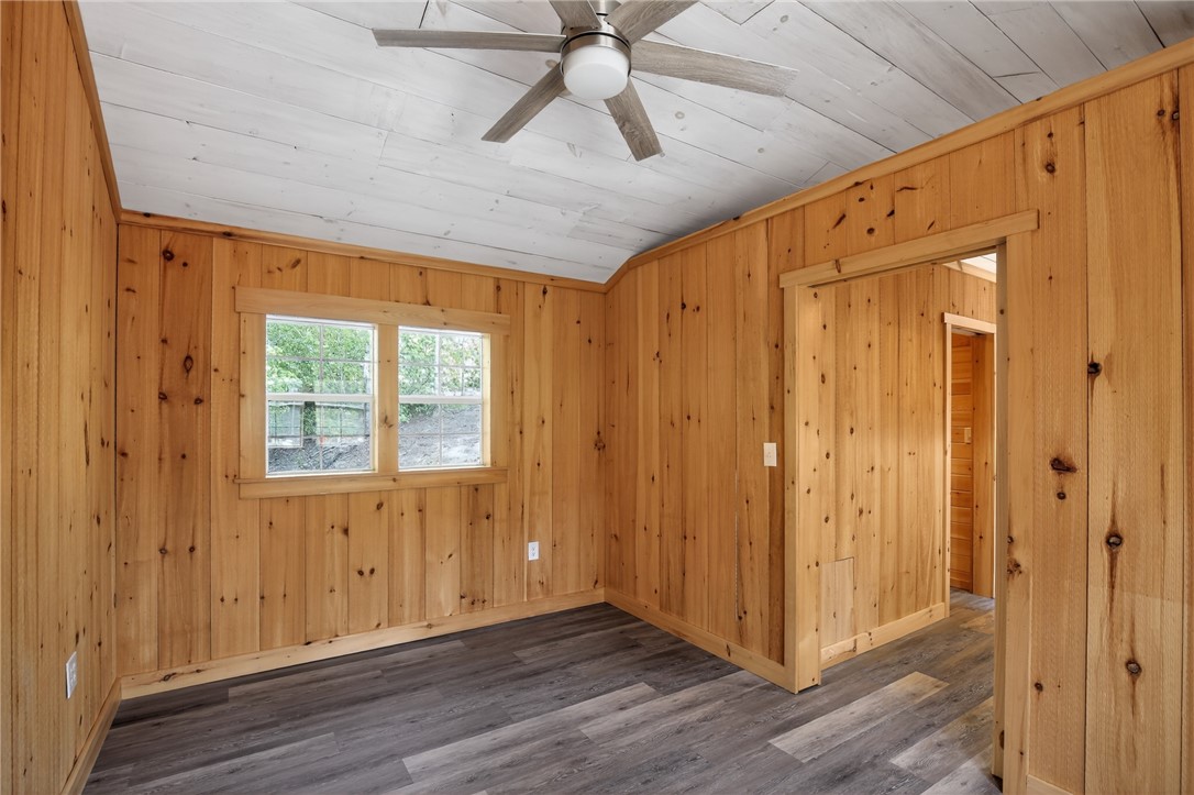 400 Mill Creek Road Sunset, SC 29685 - Photo 5 of 8 Wood-paneled walls and a ceiling fan create a warm, inviting atmosphere in this versatile interior space.