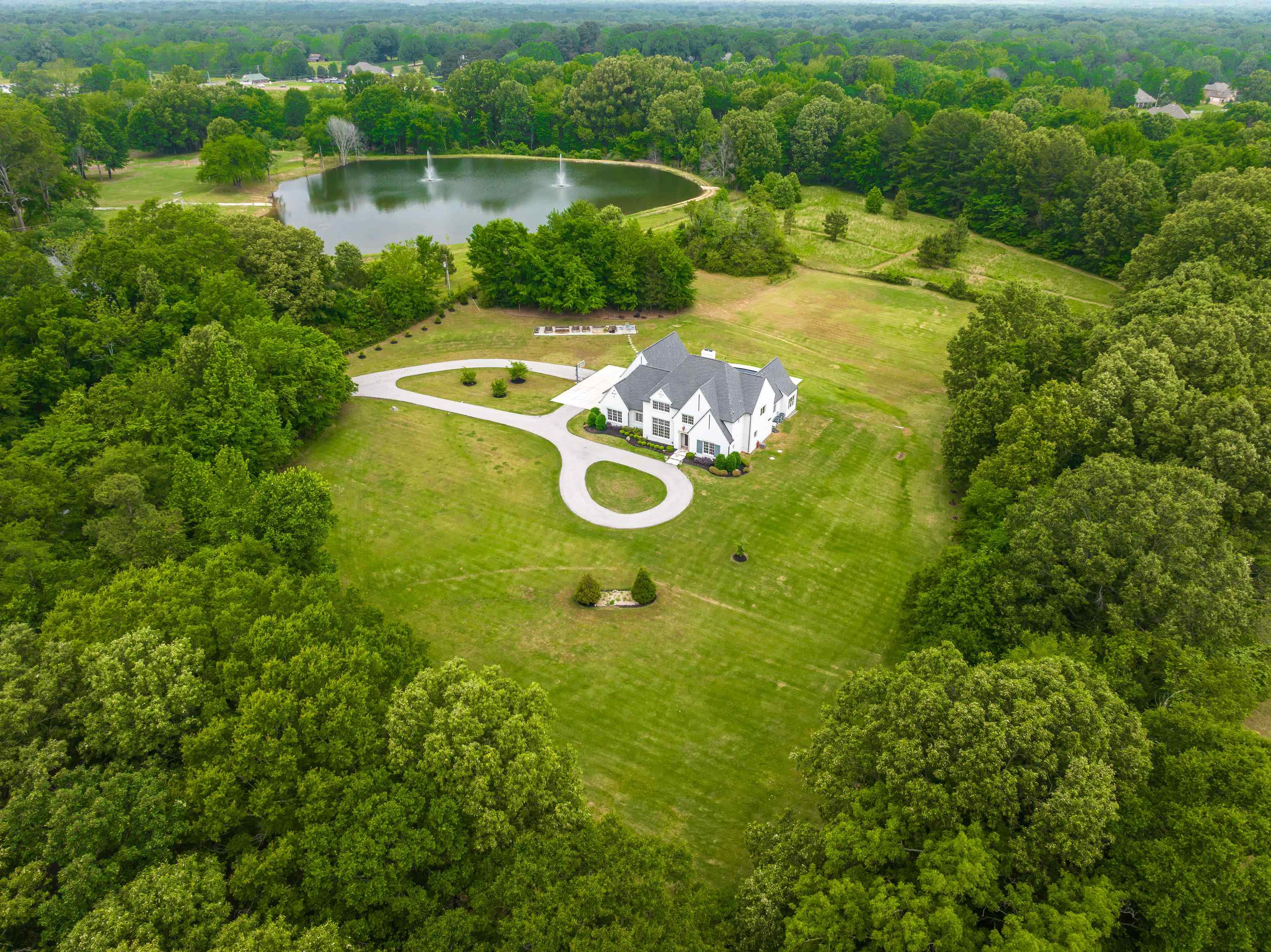 55 East Old State Line Road Piperton, TN 38017 - Photo 1 of 40 Expansive property featuring a white residence with a dark roof, a circular driveway, a private pond with two fountains, and mature trees