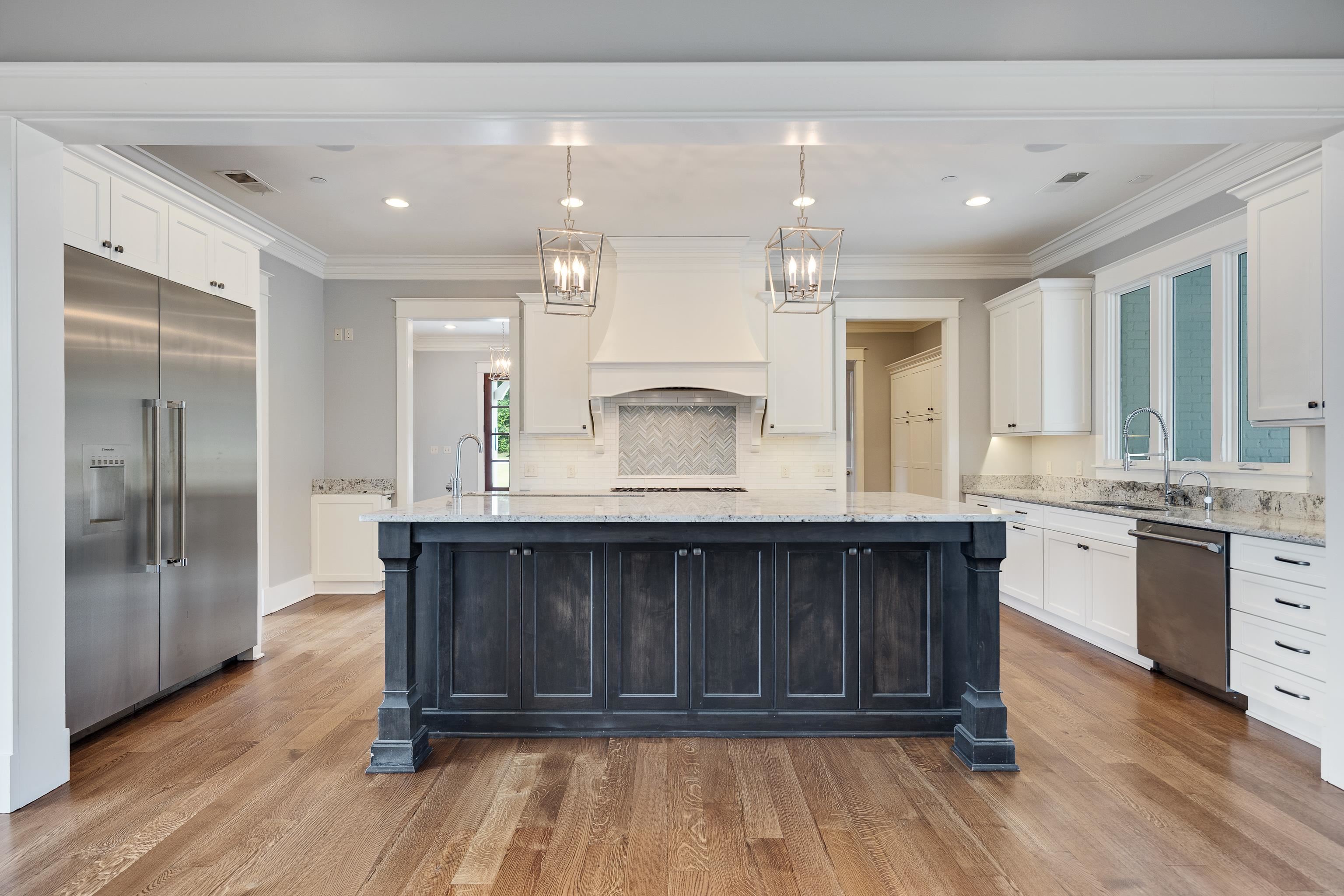 55 East Old State Line Road Piperton, TN 38017 - Photo 11 of 40 Gourmet kitchen featuring a substantial dark-stained island with a light-toned countertop, stainless steel appliances, white cabinetry, and wood-finish flooring