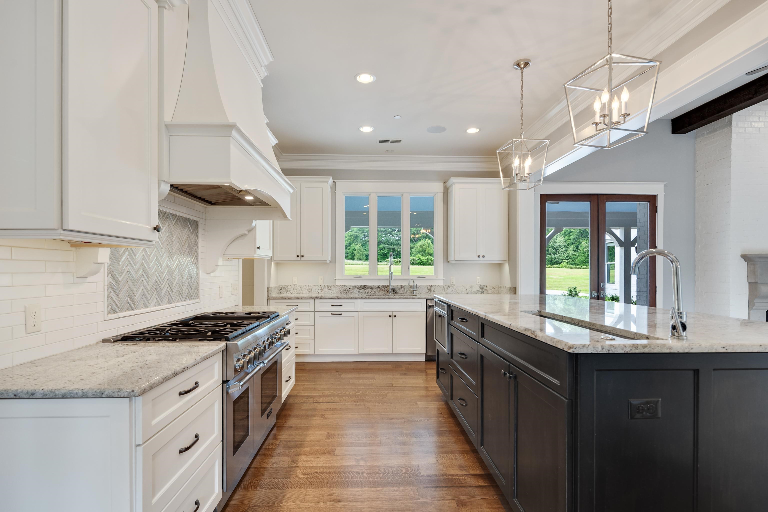 55 East Old State Line Road Piperton, TN 38017 - Photo 13 of 40 Gourmet kitchen featuring a large central island with a built-in sink, stainless steel appliances, white cabinetry, and hardwood flooring
