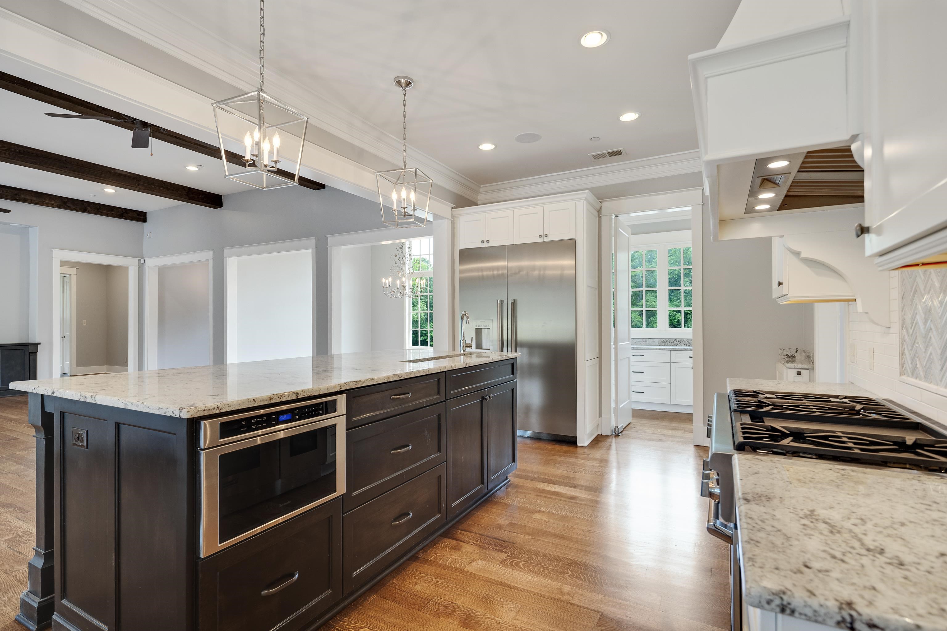55 East Old State Line Road Piperton, TN 38017 - Photo 14 of 40 Spacious kitchen featuring a large island with an integrated microwave, wood-finish flooring, recessed lighting, and stainless steel appliances