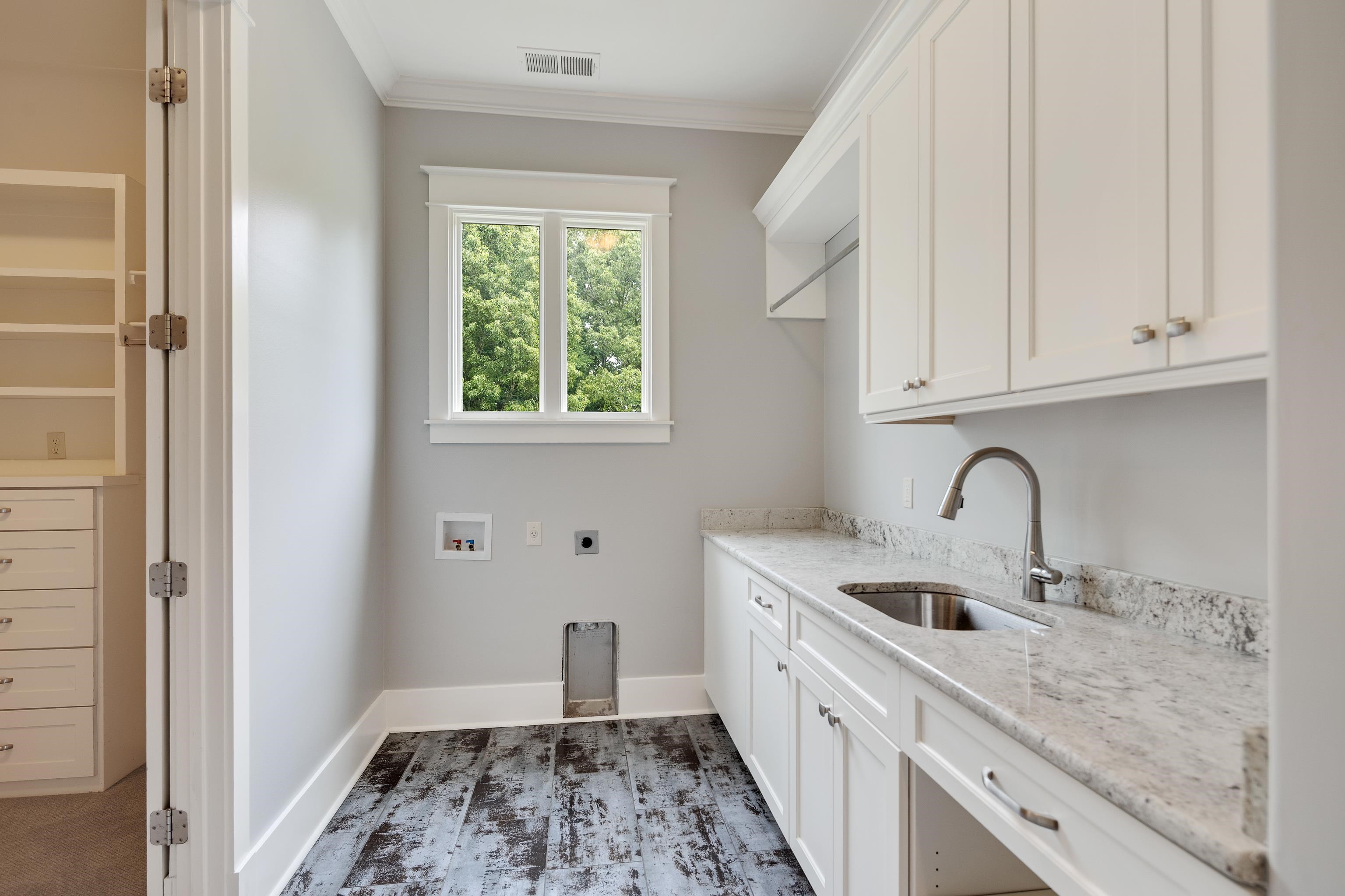 55 East Old State Line Road Piperton, TN 38017 - Photo 26 of 40 Laundry area featuring white cabinetry, light-toned stone countertop, undermount sink with gooseneck faucet, and wood-finish flooring