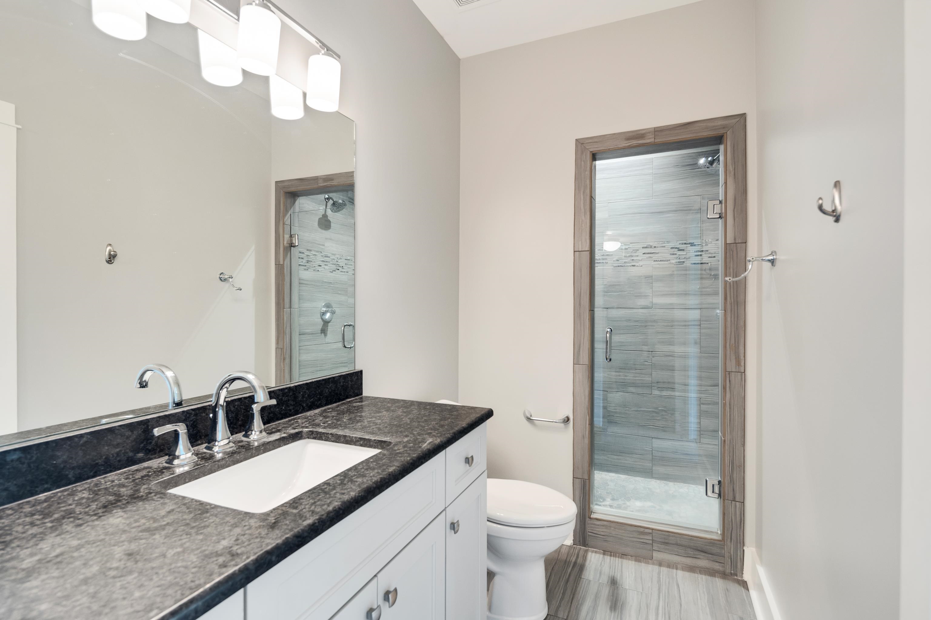 55 East Old State Line Road Piperton, TN 38017 - Photo 35 of 40 Modern bathroom featuring a single vanity with a dark countertop, an undermount sink, and chrome fixtures