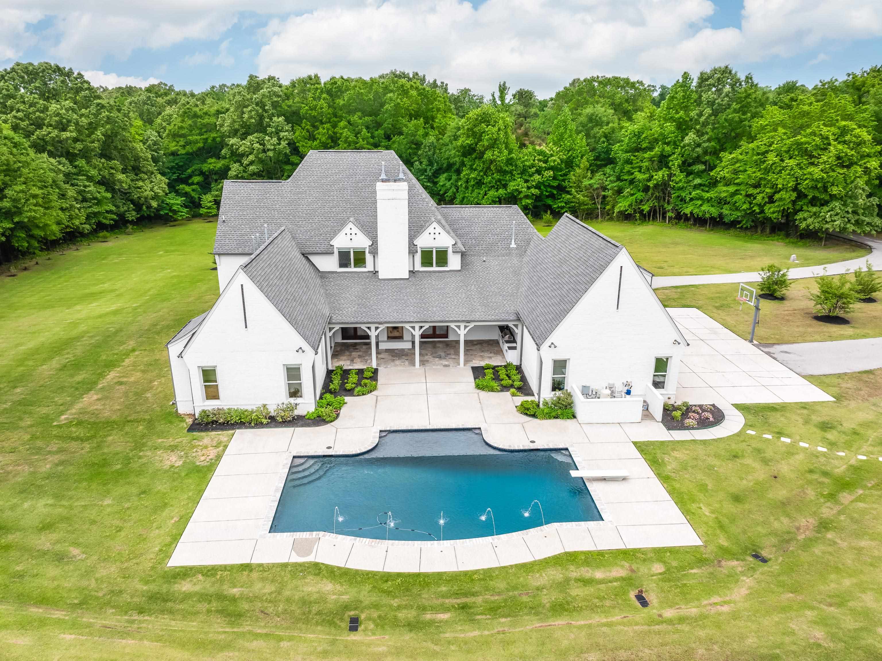 55 East Old State Line Road Piperton, TN 38017 - Photo 5 of 40 Rear exterior featuring a large swimming pool with integrated fountains, expansive concrete decking, and a diving board