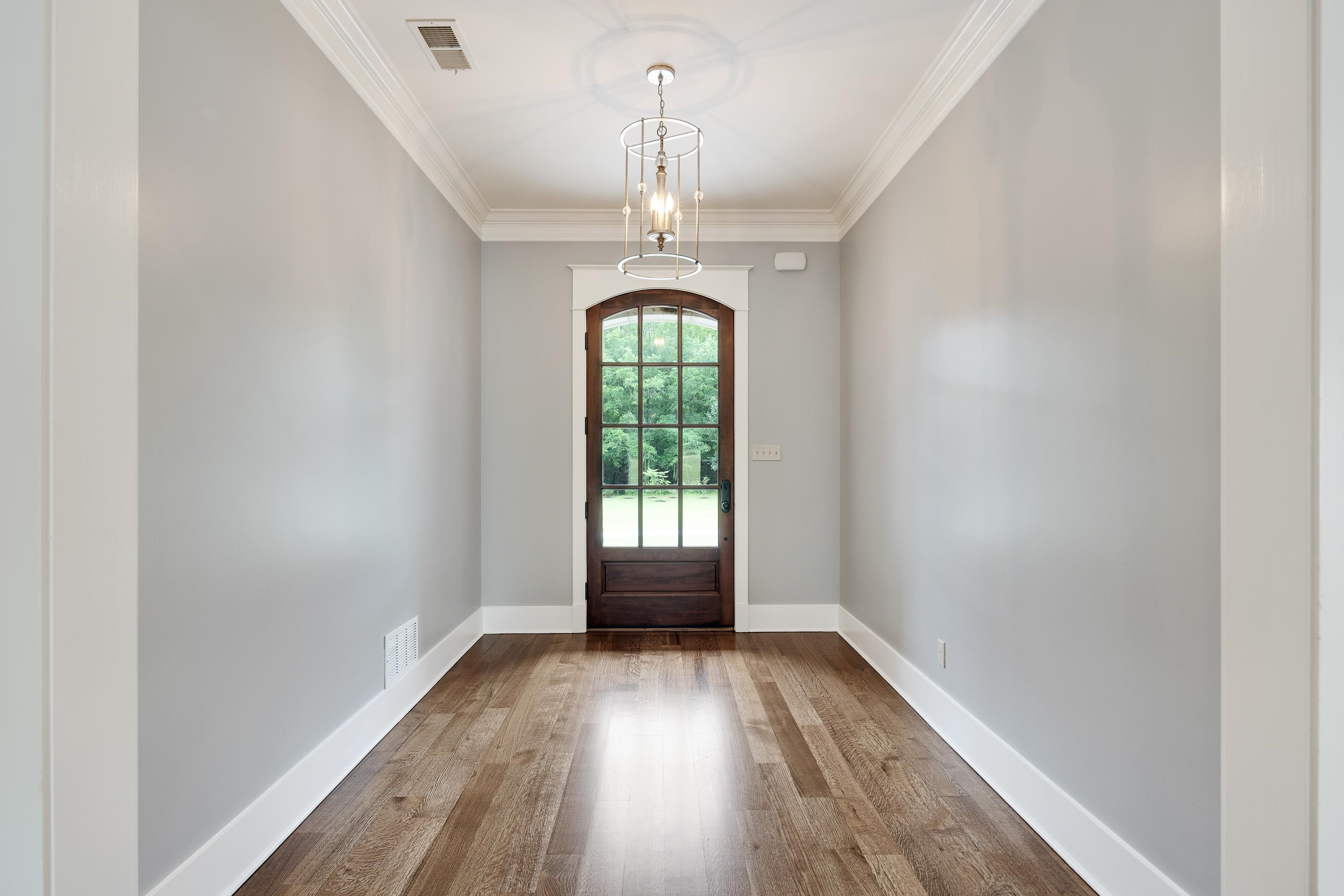 55 East Old State Line Road Piperton, TN 38017 - Photo 6 of 40 Arched wood-panel door with glass inserts, wood-finish flooring, crown molding, a decorative ceiling medallion, and a suspended lantern-style light fixture