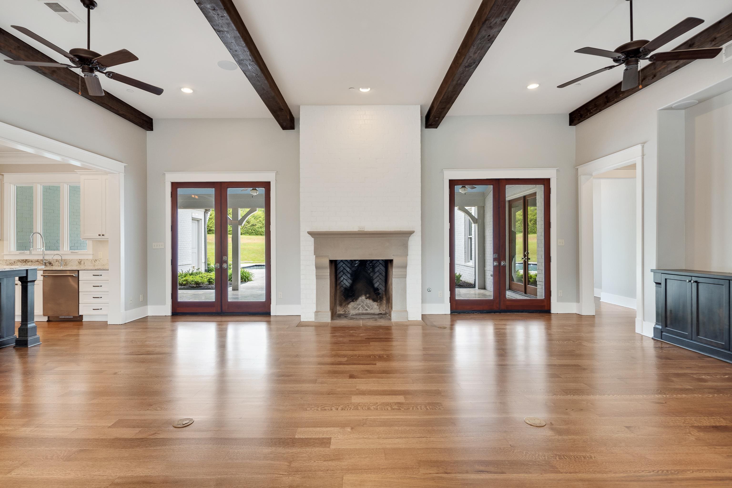 55 East Old State Line Road Piperton, TN 38017 - Photo 8 of 40 Spacious living area featuring exposed wood ceiling beams, hardwood flooring, a stone fireplace, and double glass-paneled doors