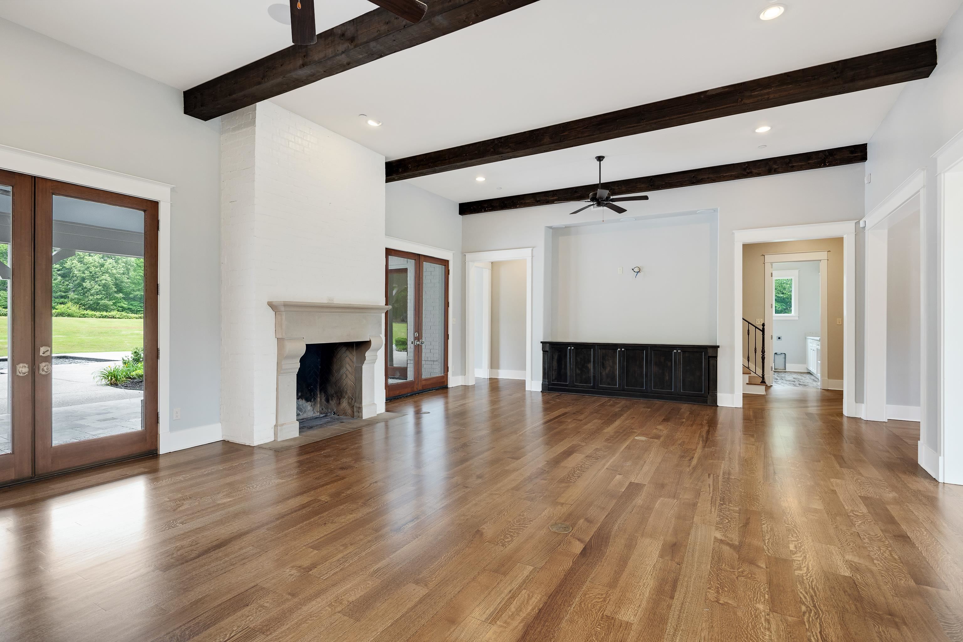 55 East Old State Line Road Piperton, TN 38017 - Photo 9 of 40 Spacious living area featuring wood-finish flooring, exposed ceiling beams, a stone fireplace, and multiple French doors