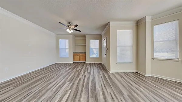 a view of empty room with wooden floor and fan