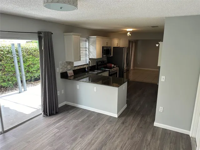 a kitchen with granite countertop a sink stove and cabinets