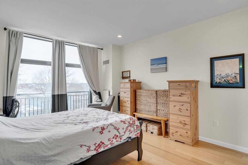 251 Heath Street, Unit 421 Boston, MA 02130 - Photo 13 of 20 a bedroom with a bed a dresser and a large window