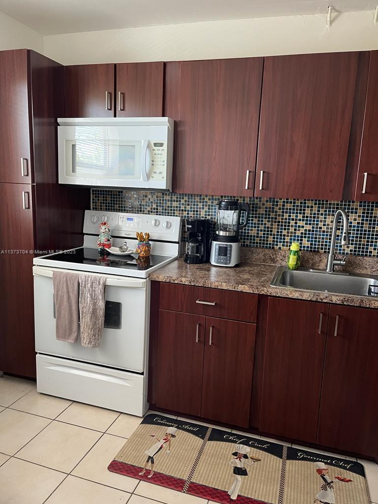 8340 Sands Point Boulevard, Unit P309 Tamarac, FL 33321 - Photo 20 of 33 a kitchen with stainless steel appliances granite countertop a sink stove and cabinets