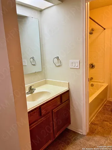 a bathroom with a granite countertop sink mirror and a bathtub