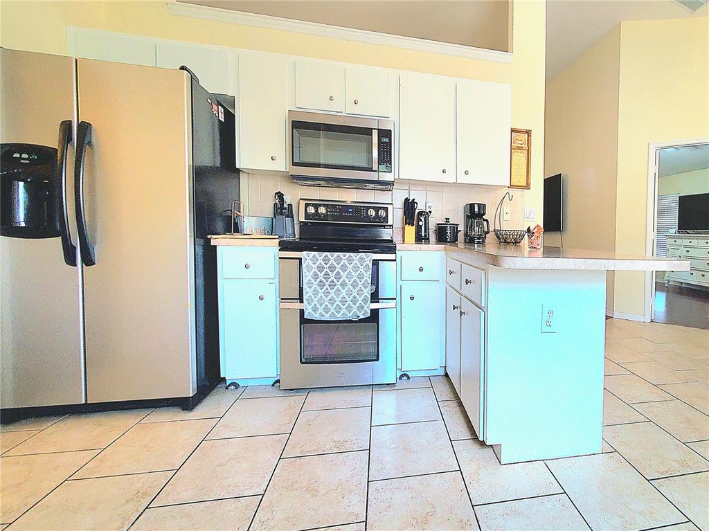 13599 Southeast 51st Terrace Summerfield, FL 34491 - Photo 13 of 44 a kitchen with stainless steel appliances granite countertop a refrigerator a stove top oven and a sink