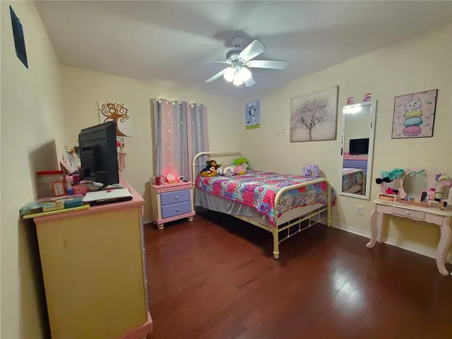 a bedroom with a bed a dresser and paintings on the wall