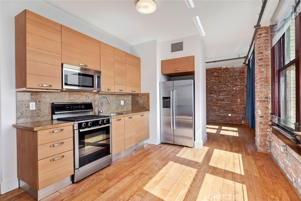460 South Spring Street, Unit 802 Los Angeles, CA 90013 - Photo 15 of 25 a kitchen with stainless steel appliances a stove top oven a sink and a refrigerator