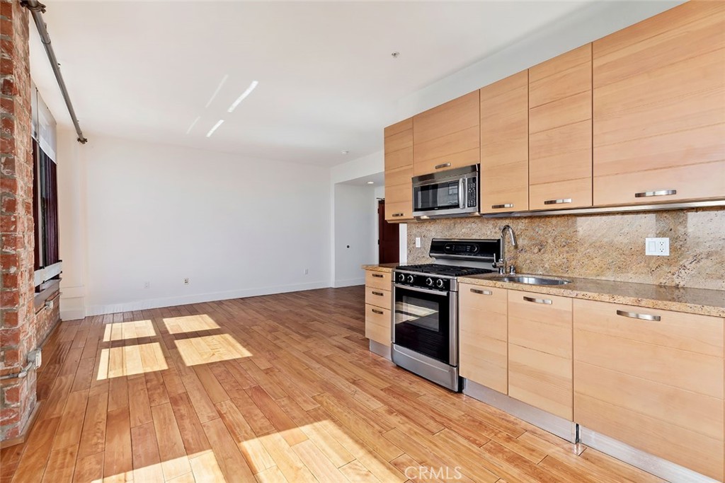 460 South Spring Street, Unit 802 Los Angeles, CA 90013 - Photo 16 of 25 a kitchen with granite countertop a stove a sink and a microwave