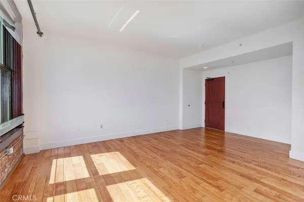 a view of an empty room with a window and wooden floor