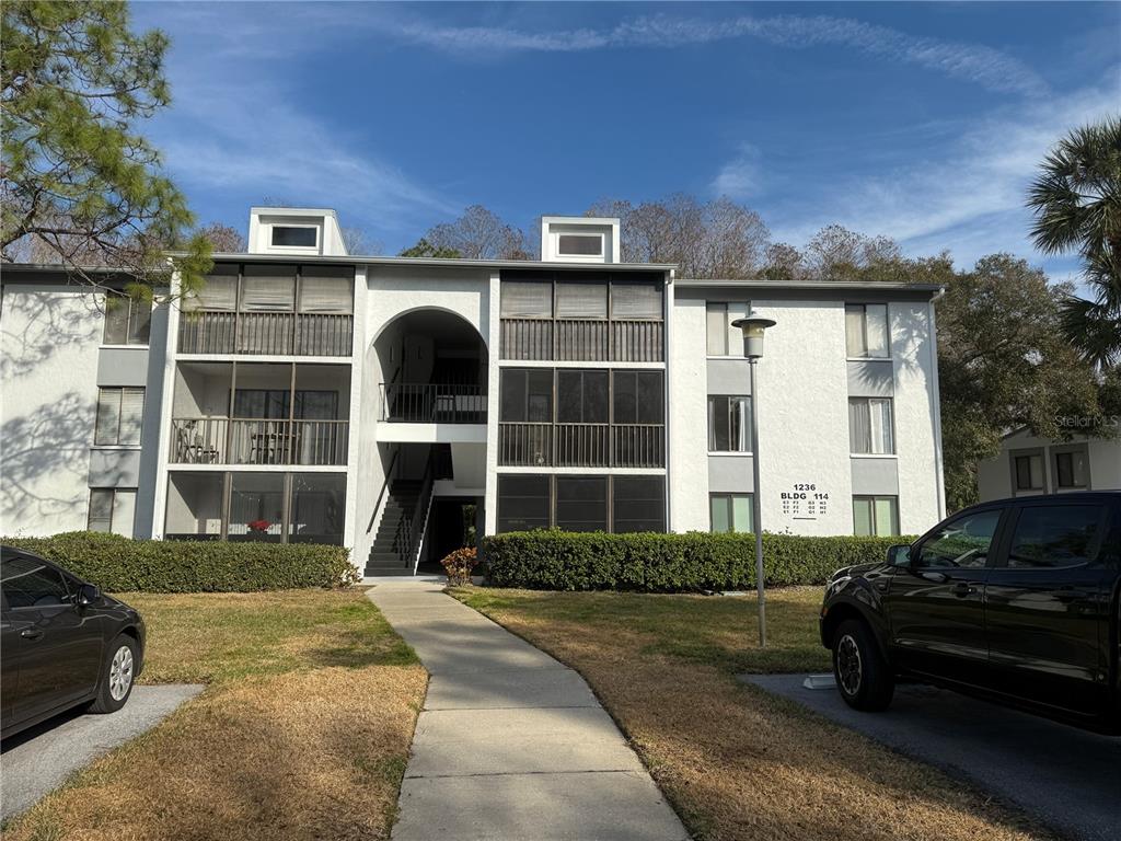 1236 Pine Ridge Circle West, Unit G3 Tarpon Springs, FL 34688 - Photo 1 of 18 a front view of a house with a yard glass top table and chairs