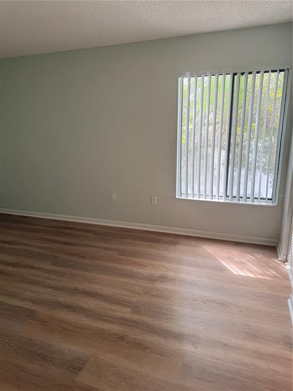 1236 Pine Ridge Circle West, Unit G3 Tarpon Springs, FL 34688 - Photo 11 of 18 a view of an empty room with wooden floor and a window