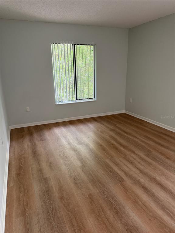 1236 Pine Ridge Circle West, Unit G3 Tarpon Springs, FL 34688 - Photo 9 of 18 a view of an empty room with wooden floor and a window