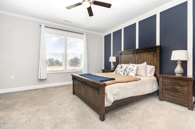 a bedroom with a large bed and a chandelier fan