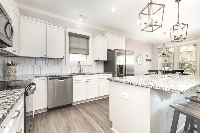 a kitchen with granite countertop a sink cabinets stainless steel appliances and a counter top space