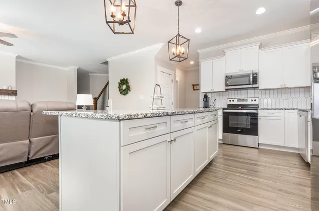 a kitchen with kitchen island granite countertop stainless steel appliances cabinets a sink and a wooden floor