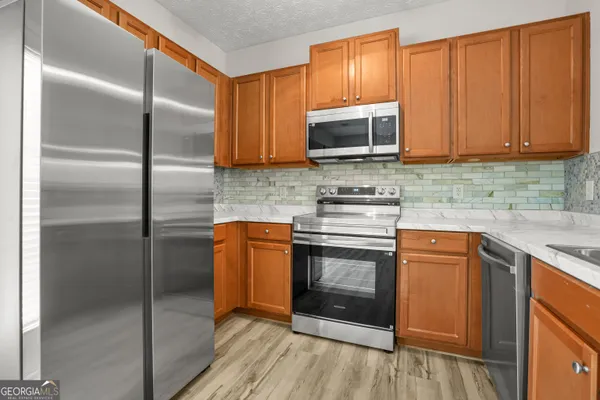 a kitchen with stainless steel appliances granite countertop a refrigerator a stove a sink and a microwave