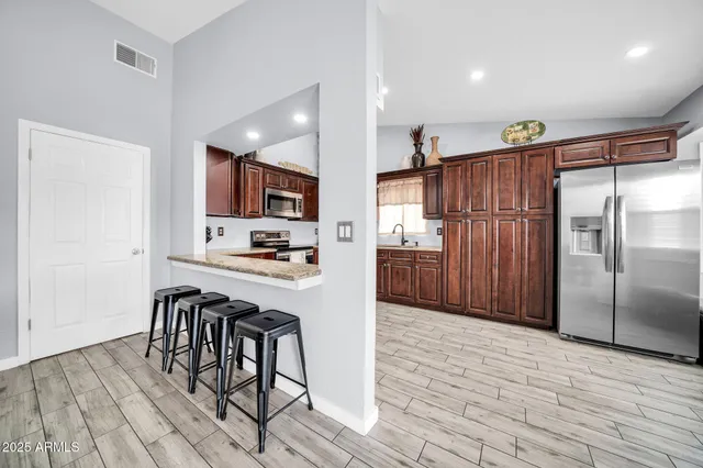 a kitchen with granite countertop a refrigerator and a stove top oven