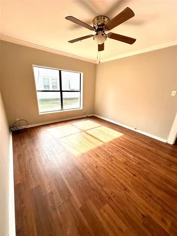 an empty room with wooden floor fan and windows