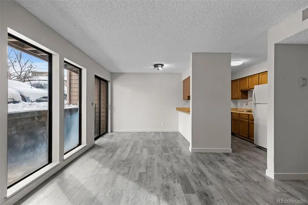 an empty room with wooden floor fireplace and windows