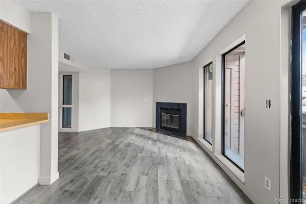 a view of an empty room with wooden floor fireplace and a window