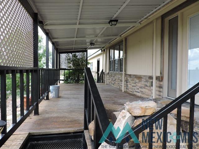 35 Mays Road Clayton, NM 88415 - Photo 5 of 31 Covered porch with wood-finish decking, black metal railings, and lattice privacy screens