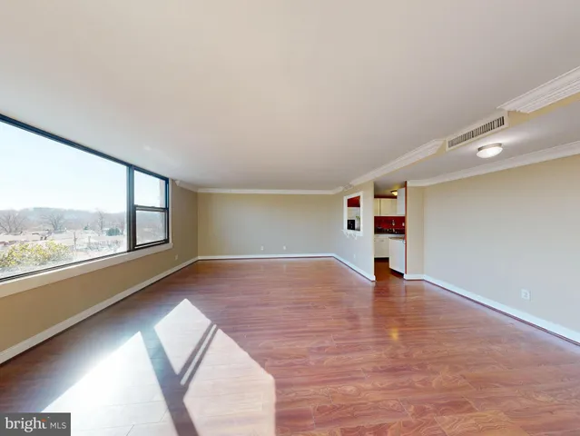 a view of an empty room with a window and wooden floor