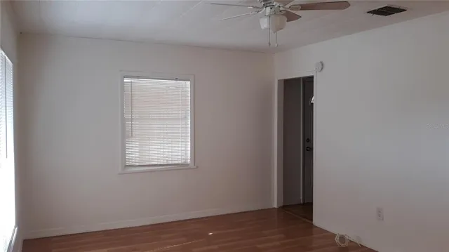 an empty room with a window and a ceiling fan