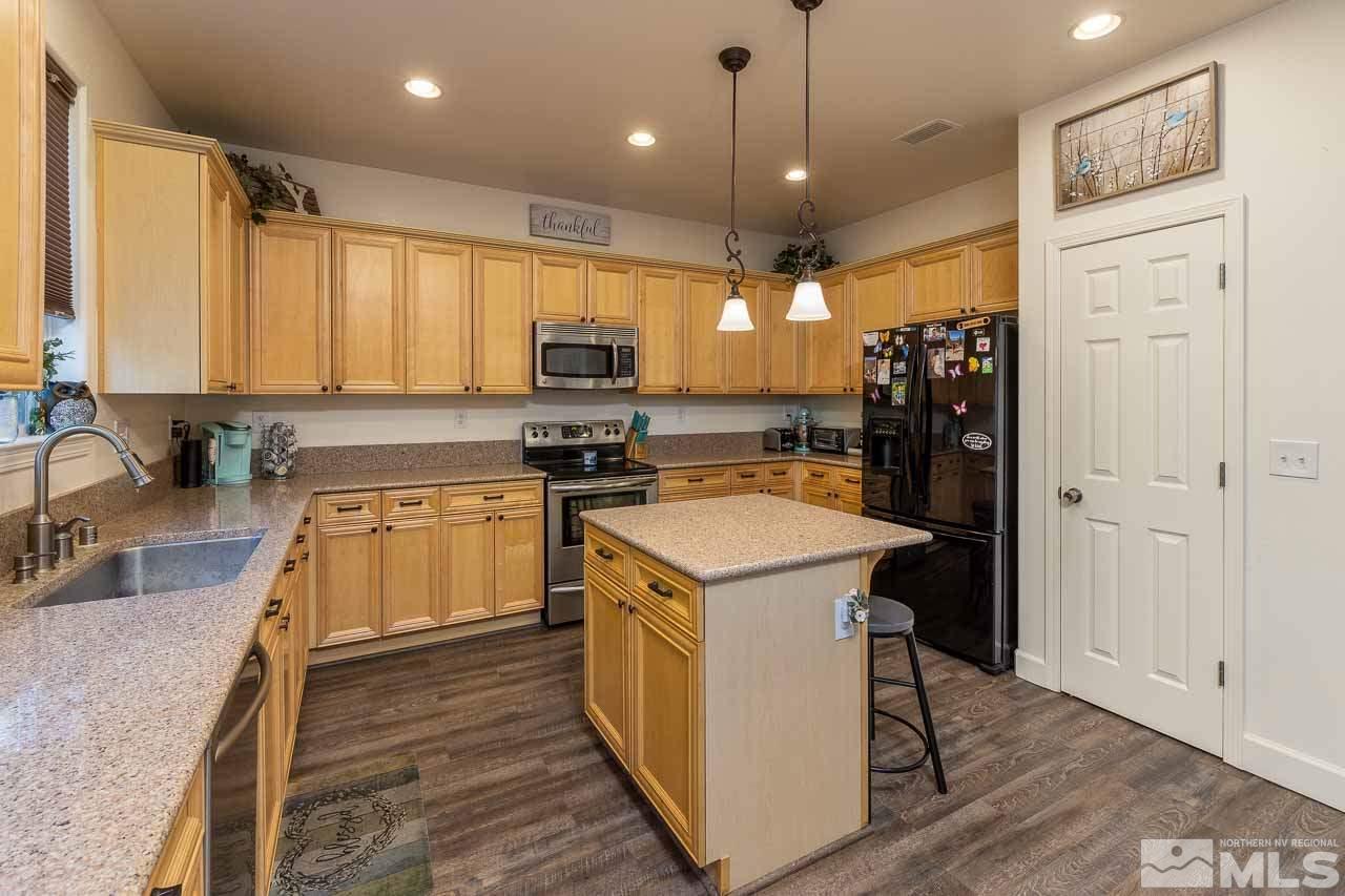 9150 Sunrock Road Reno, NV 89521 - Photo 9 of 19 a kitchen with a refrigerator a sink and wooden cabinets