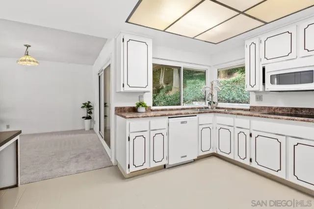 a kitchen with stainless steel appliances granite countertop a stove a sink and a granite counter tops with white cabinets