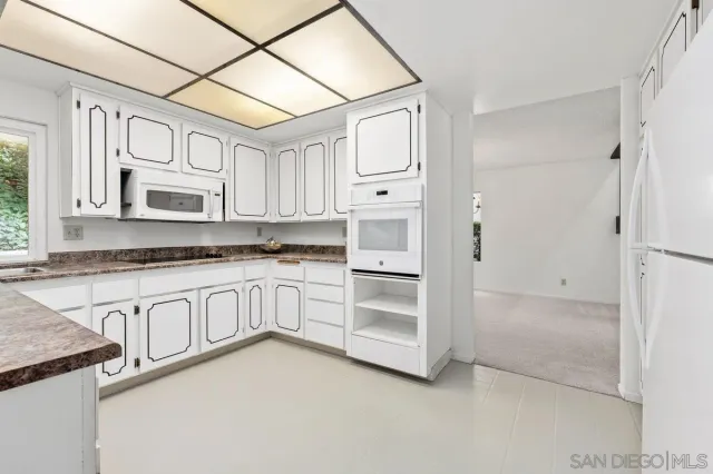 a kitchen with granite countertop white cabinets and white appliances