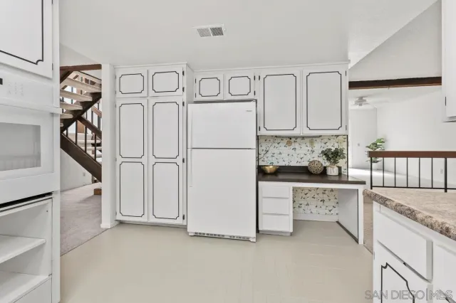 a kitchen with white cabinets and refrigerator