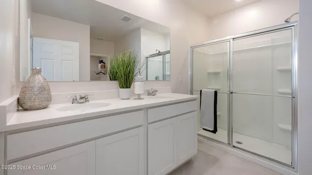 a bathroom with a double vanity sink mirror and shower