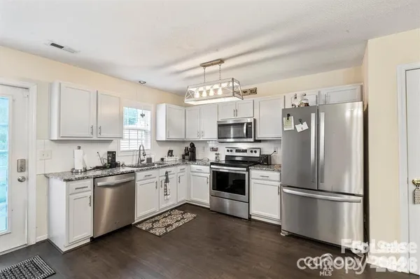 a kitchen with stainless steel appliances a refrigerator a stove top oven a sink and cabinets
