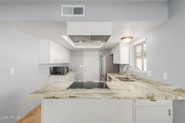 a kitchen with stainless steel appliances granite countertop a sink and a white cabinets