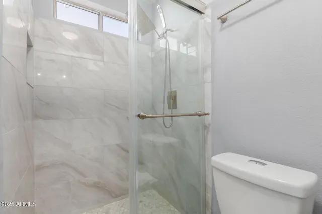 a white toilet sitting next to a shower