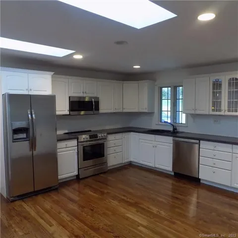 a kitchen with granite countertop a refrigerator and a stove top oven