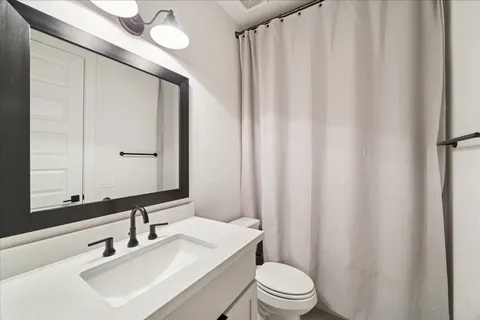 a bathroom with a sink a toilet a mirror and shower curtain
