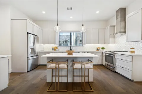 a kitchen with a white center island and stainless steel appliances
