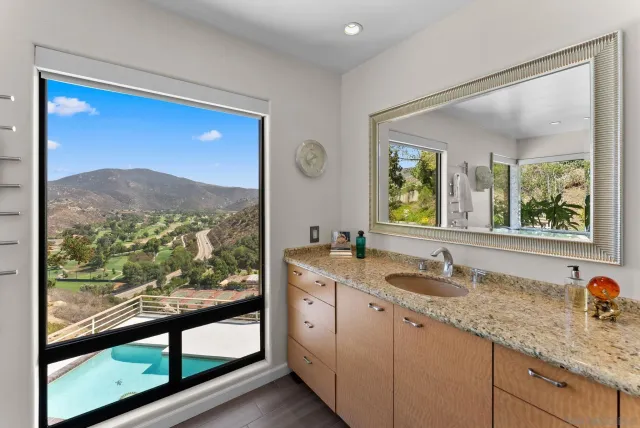a bathroom with a granite countertop sink mirror vanity and next to a window
