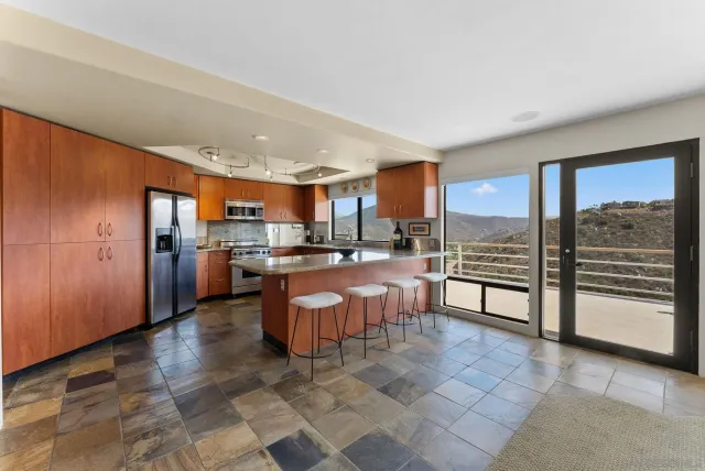 a open kitchen with stainless steel appliances granite countertop a refrigerator stove top oven and a sink with granite countertops