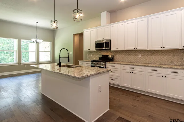 a kitchen with stainless steel appliances granite countertop a sink a stove and a microwave